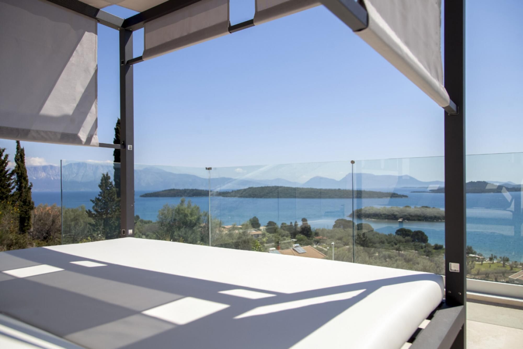 Een moderne slaapkamer met een groot raam met uitzicht op een schilderachtig meer en bergen.
