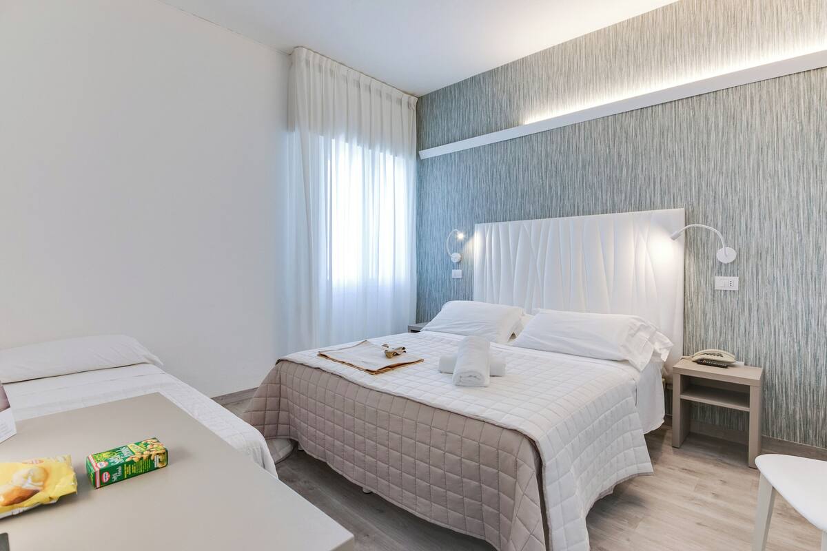 Una habitación de hotel con cama, mesita de noche y una silla.