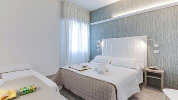 A hotel room with a bed, bedside table, and a chair.