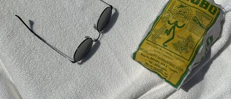 A pair of sunglasses and a yellow package on a white towel.