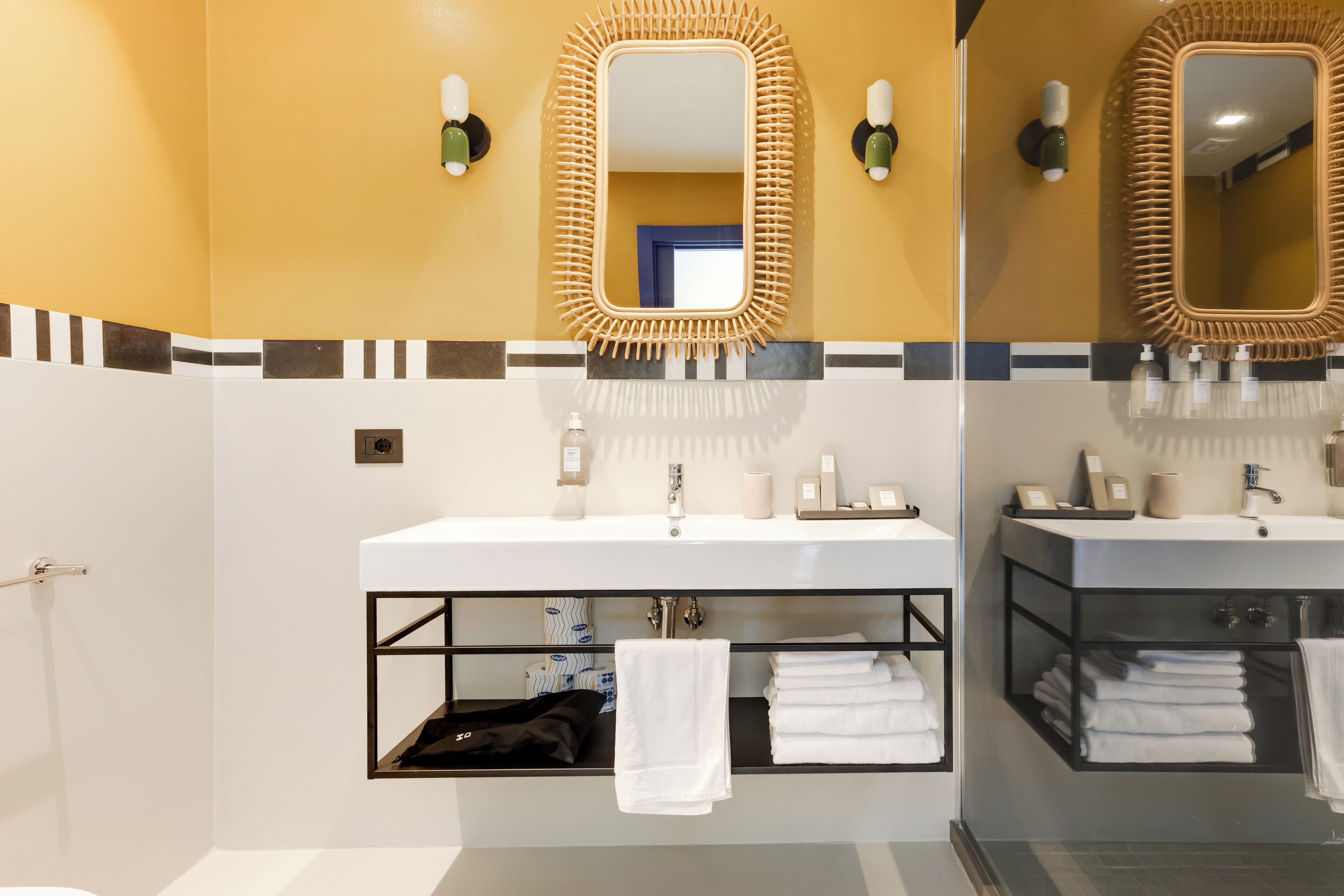 A modern bathroom with two sinks, a mirror with a decorative frame, and a towel rack.