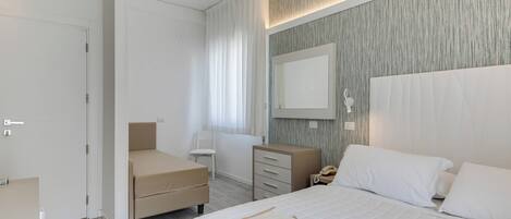 A modern bedroom with a bed, bedside table, and a mirror.