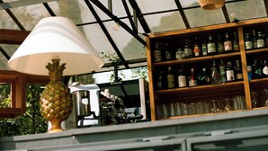 A bar area with a glass ceiling, a wooden shelf with bottles, and a pineapple-shaped lamp. - MARITTIMO® Milano Marittima (Cervia)