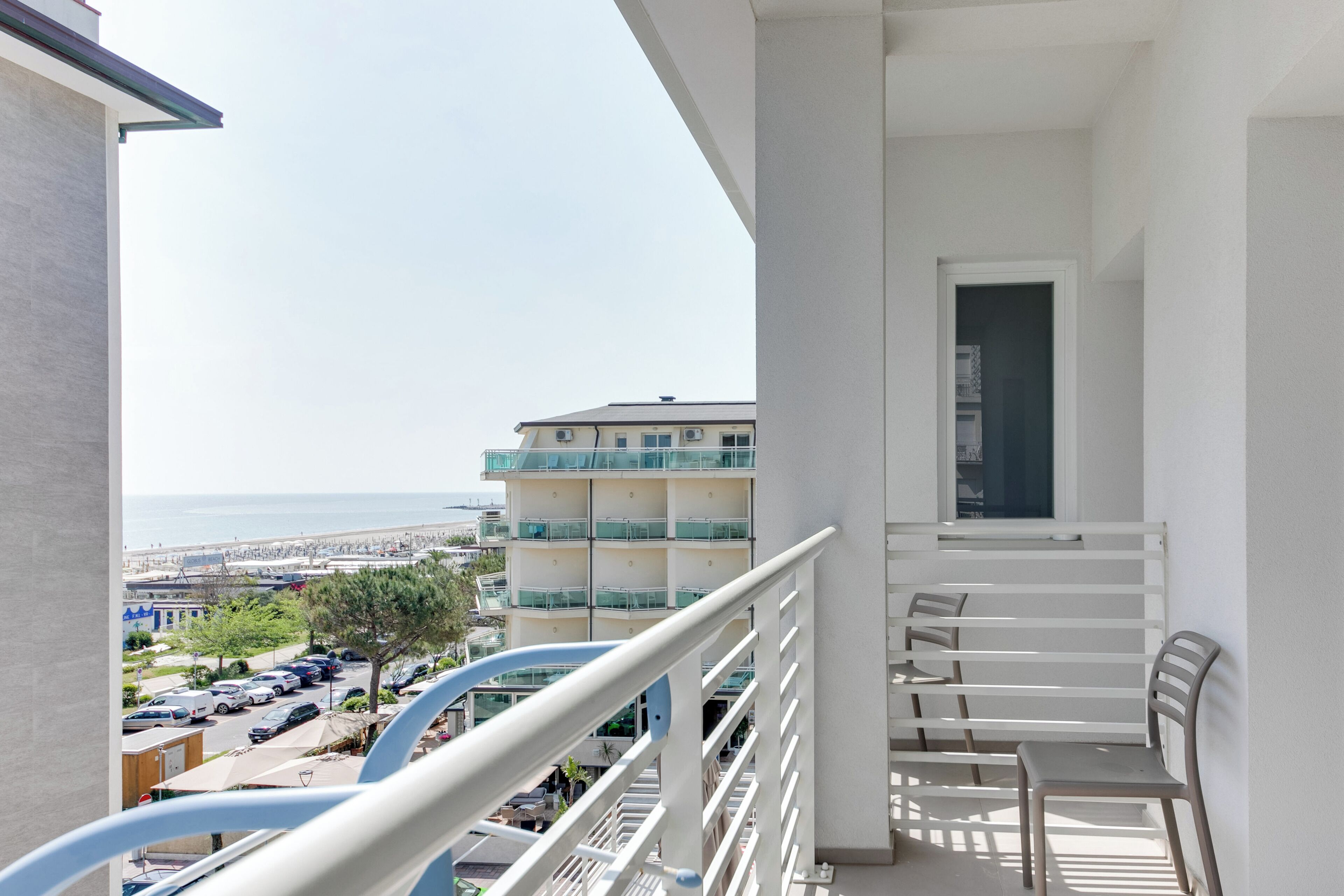 A balcony with a view of the sea and a building with balconies.