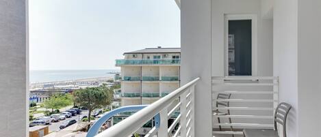 A balcony with a view of the sea and a building with balconies.
