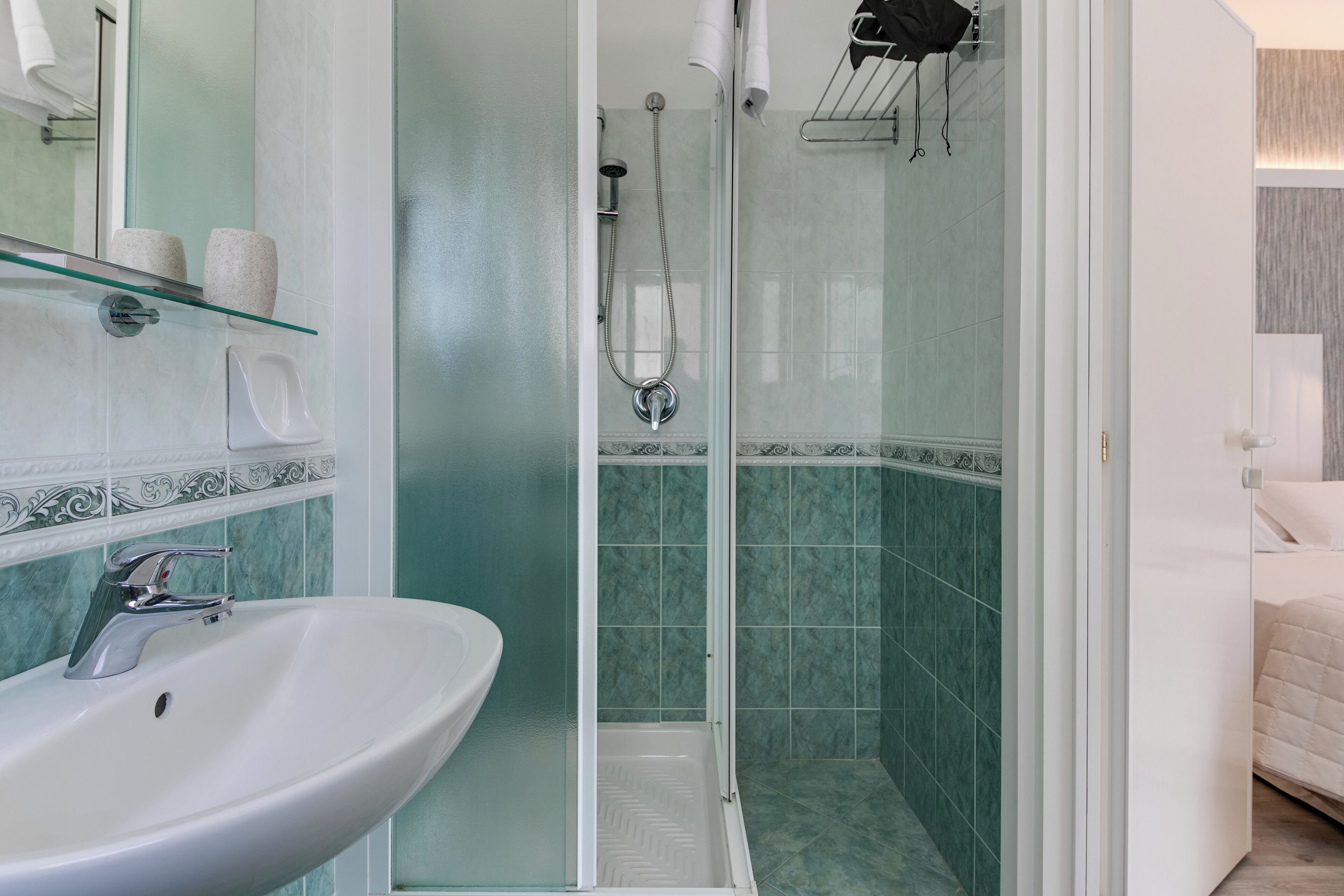 A bathroom with a glass-enclosed shower, a white sink, and a mirror.