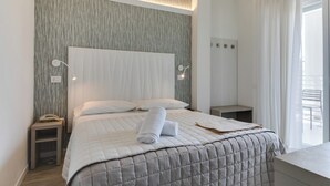 A modern hotel room with a large bed, a bedside table with a phone, and a window with curtains. - MARITTIMO® Milano Marittima (Cervia)