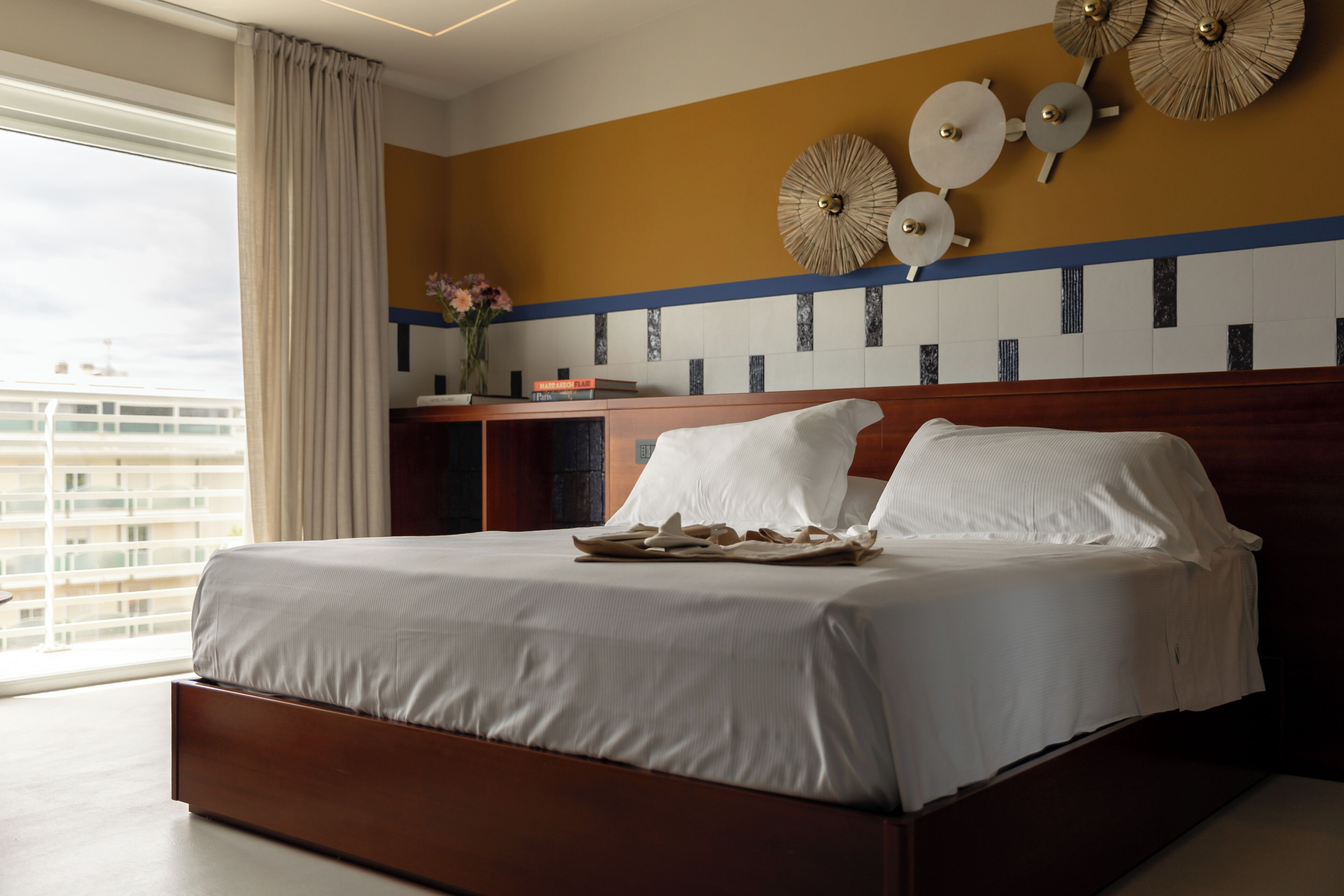 Ein Hotelzimmer mit einem großen Bett, einem Nachttisch und Blick auf die Stadt.