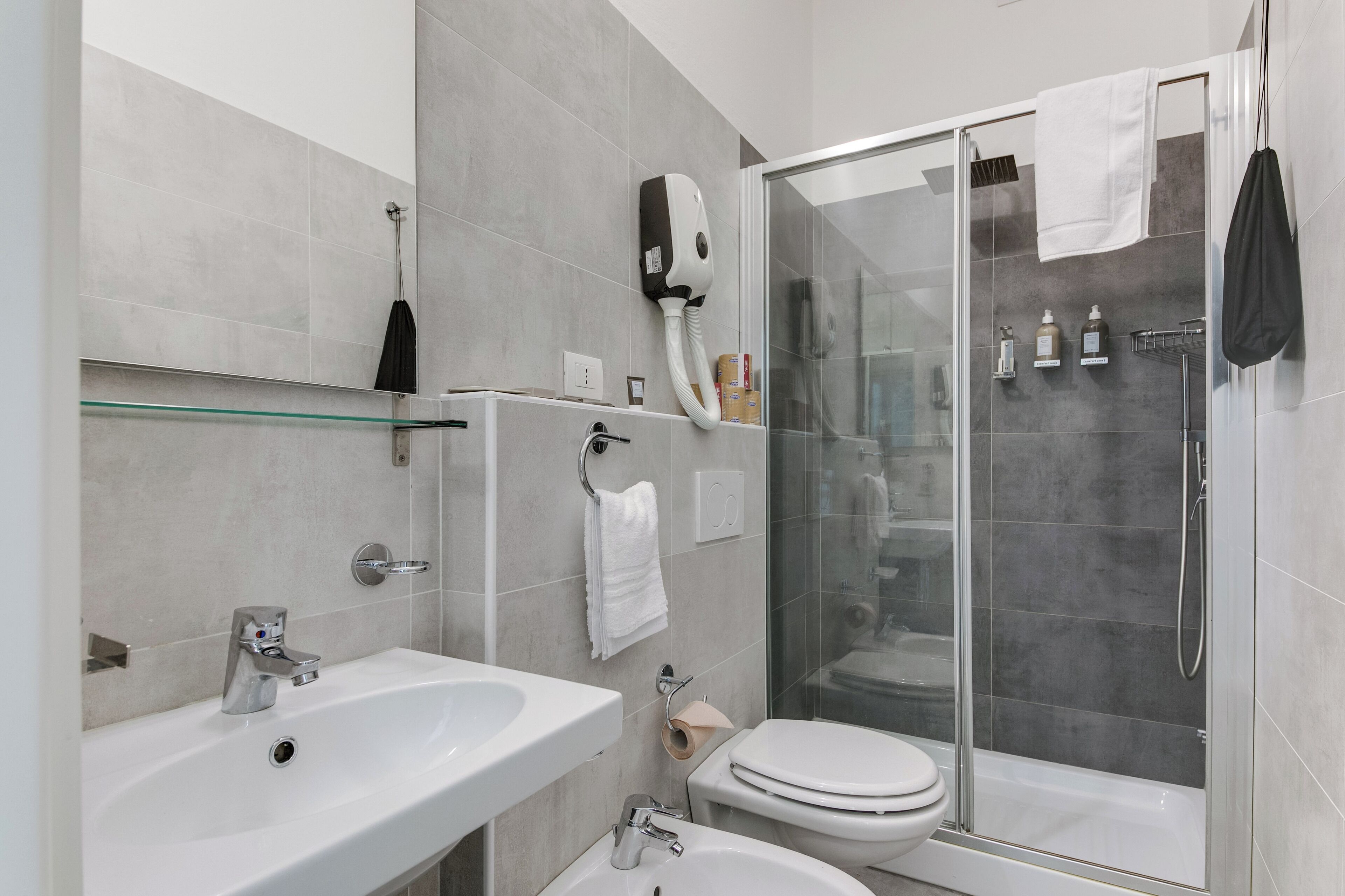 Un bagno moderno con doccia vetrata, lavandino bianco e water.