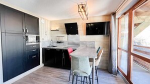 Una cocina moderna con armarios oscuros, una encimera de madera y una zona de comedor con mesa y sillas.