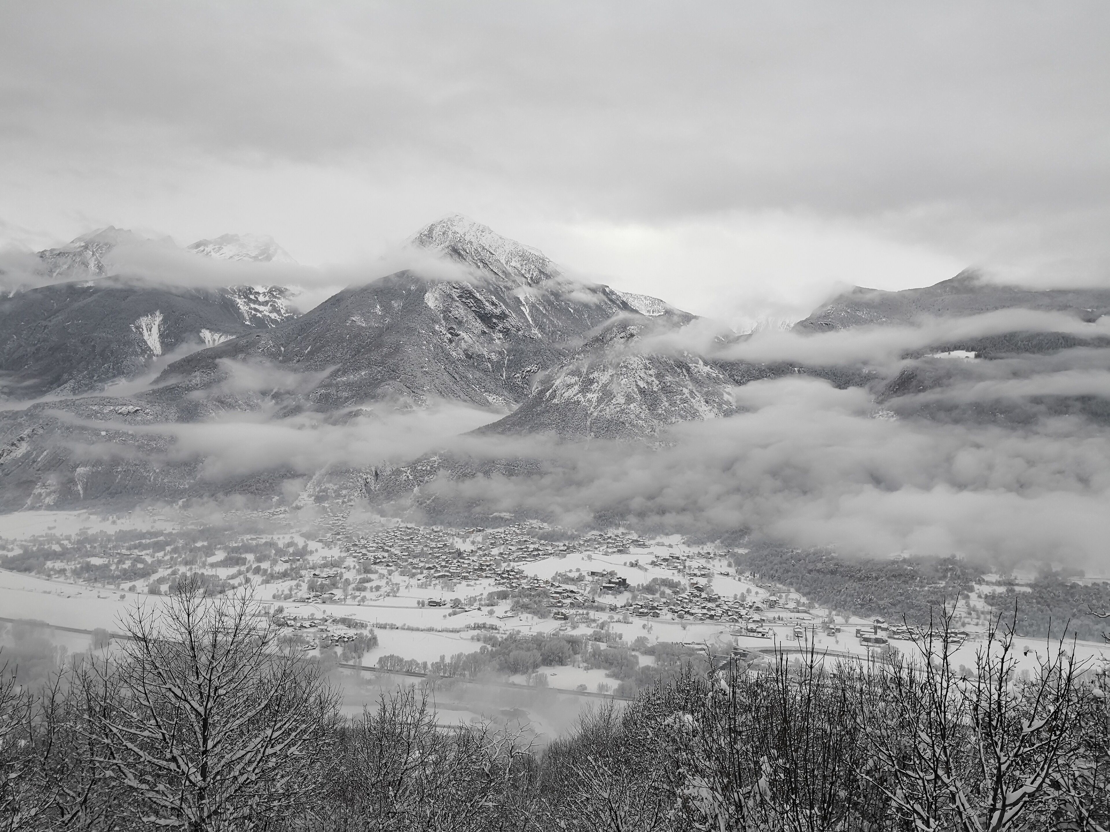 A mountainous landscape with snow-covered peaks and a town below.