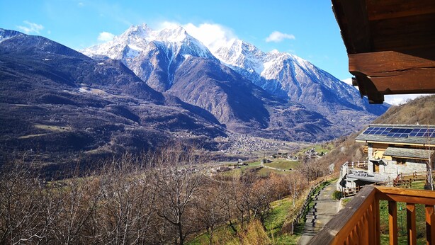 Un paysage de montagne avec une vue sur une ville et des panneaux solaires installés sur un bâtiment.