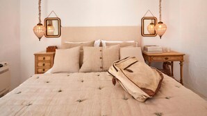 Quarto com cama grande, duas mesas de cabeceira e luminárias pendentes estilo lanterna.