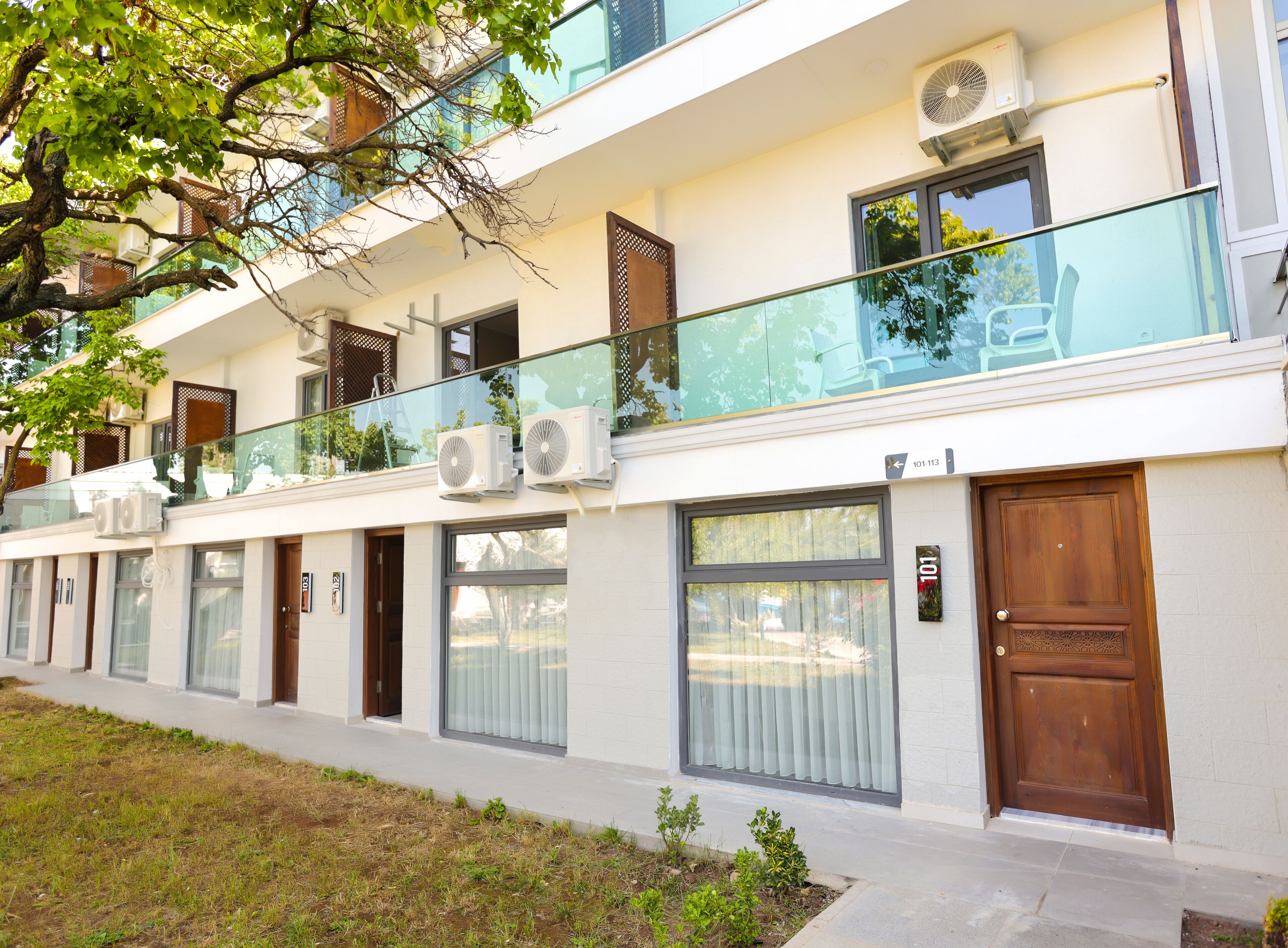 A modern building with multiple balconies, large windows, and air conditioning units.