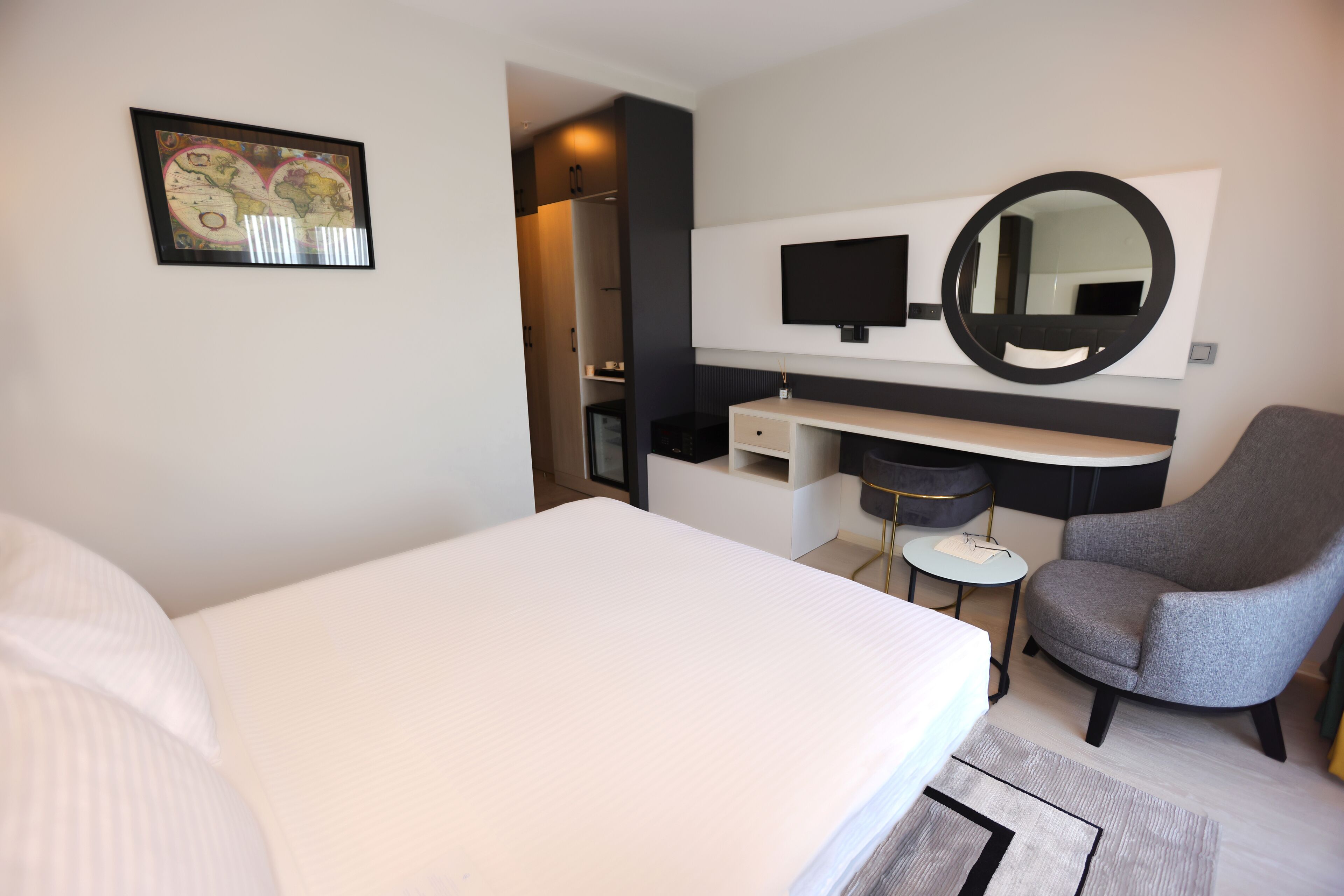 Quarto de hotel moderno com uma cama grande, uma escrivaninha, uma cadeira, uma televisão e um espelho.