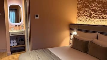 Una habitación de hotel con una cama, un tocador con espejo y una lámpara de pared.