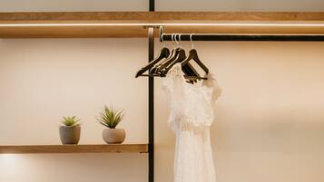 Una habitación con un banco de madera, un vestido colgado y una pila de toallas.