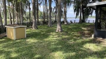 A park with a gazebo, a small yellow structure, and a lake in the background.