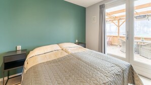 A bedroom with a bed, a nightstand, and a view of an outdoor deck. - Comfortable Holiday Home With Garden (Hellendoorn)