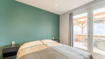 Un dormitorio con una cama, una mesita de noche y vistas a una terraza exterior.