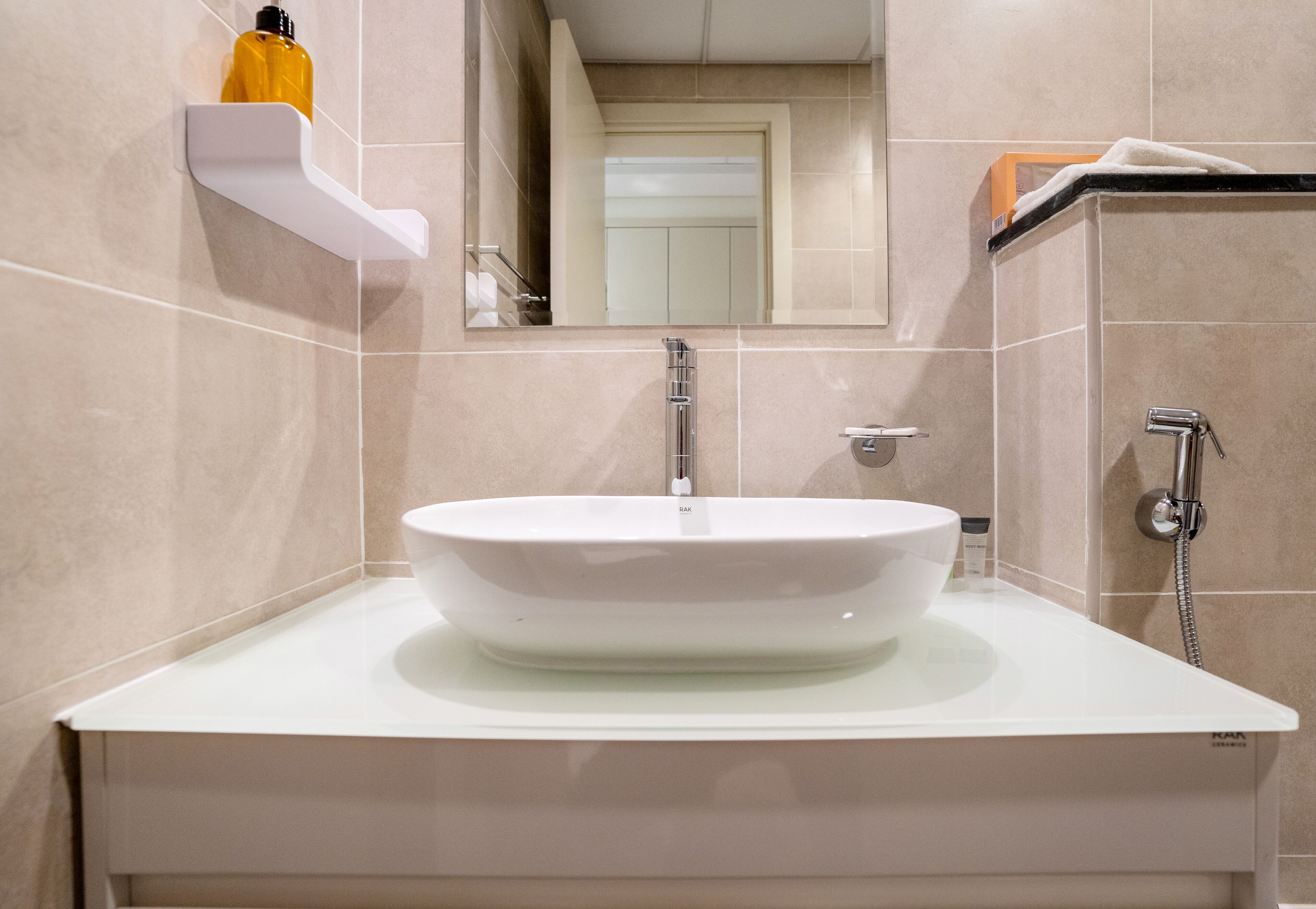 Une salle de bain avec un lavabo blanc, un miroir et une douche.