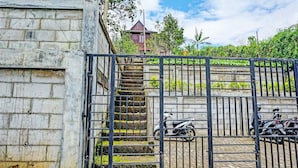 A gated area with a staircase leading to a building, surrounded by greenery and parked motorcycles.