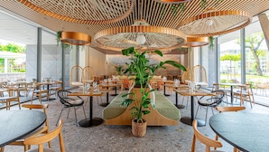 A modern restaurant with wooden furniture, a central plant, and a unique ceiling design. -  REED Boutique HOTEL & BISTRO (Siófok)