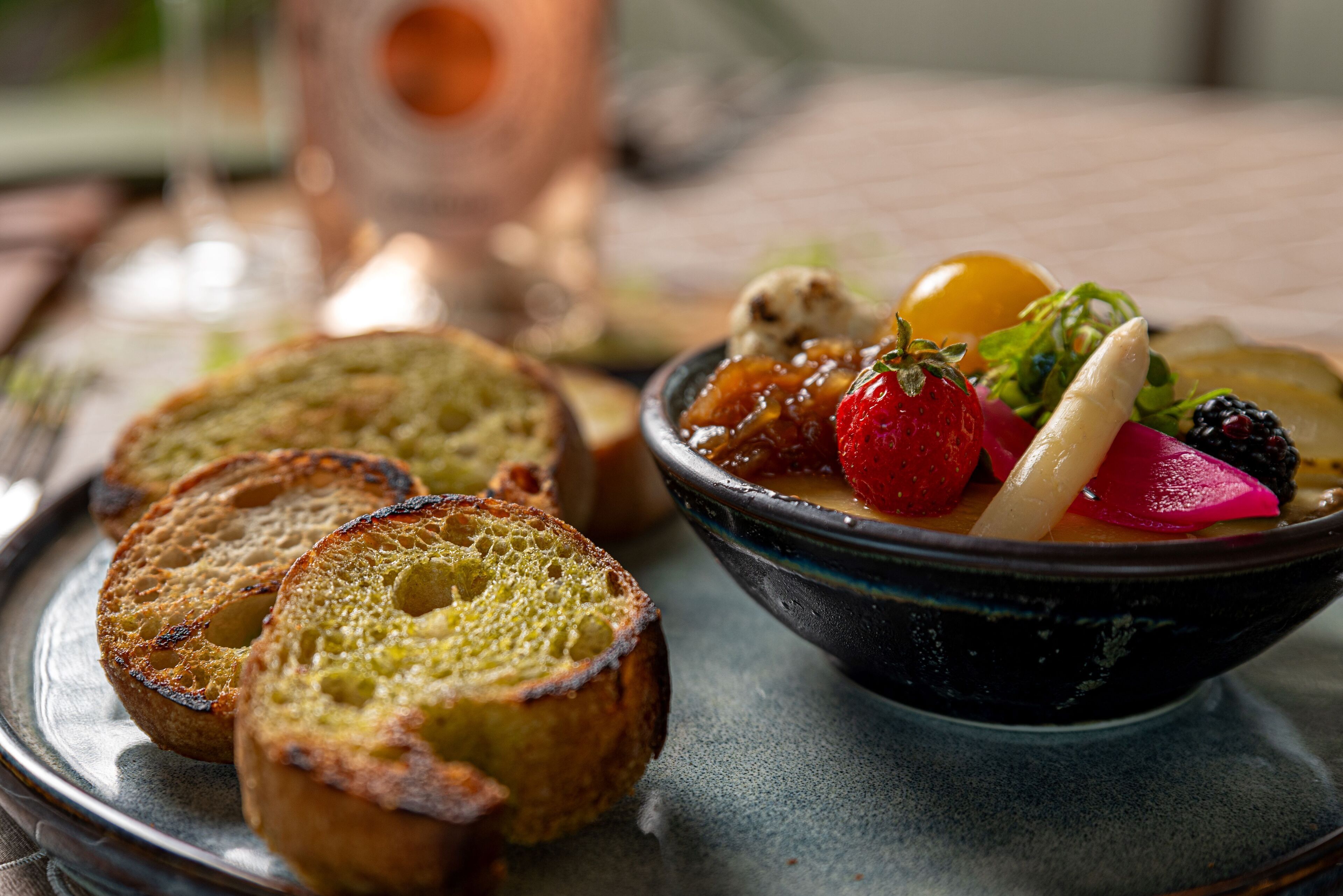 A plate with toasted bread and a bowl of fruit salad.