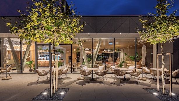 An outdoor seating area with tables and chairs, surrounded by trees and potted plants. -  REED Boutique HOTEL & BISTRO (Siófok)