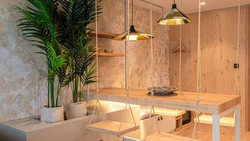 A modern dining area with a wooden table, hanging chairs, and pendant lights.