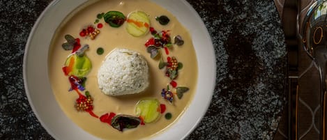 A bowl of food with a creamy sauce, garnished with various colorful toppings.