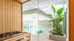 A modern interior with a wooden bench, a glass partition, and a potted plant. -  REED Boutique HOTEL & BISTRO (Siófok)
