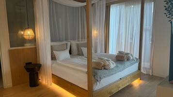 A four-poster bed with white linens, a bedside table, and a hanging lamp.