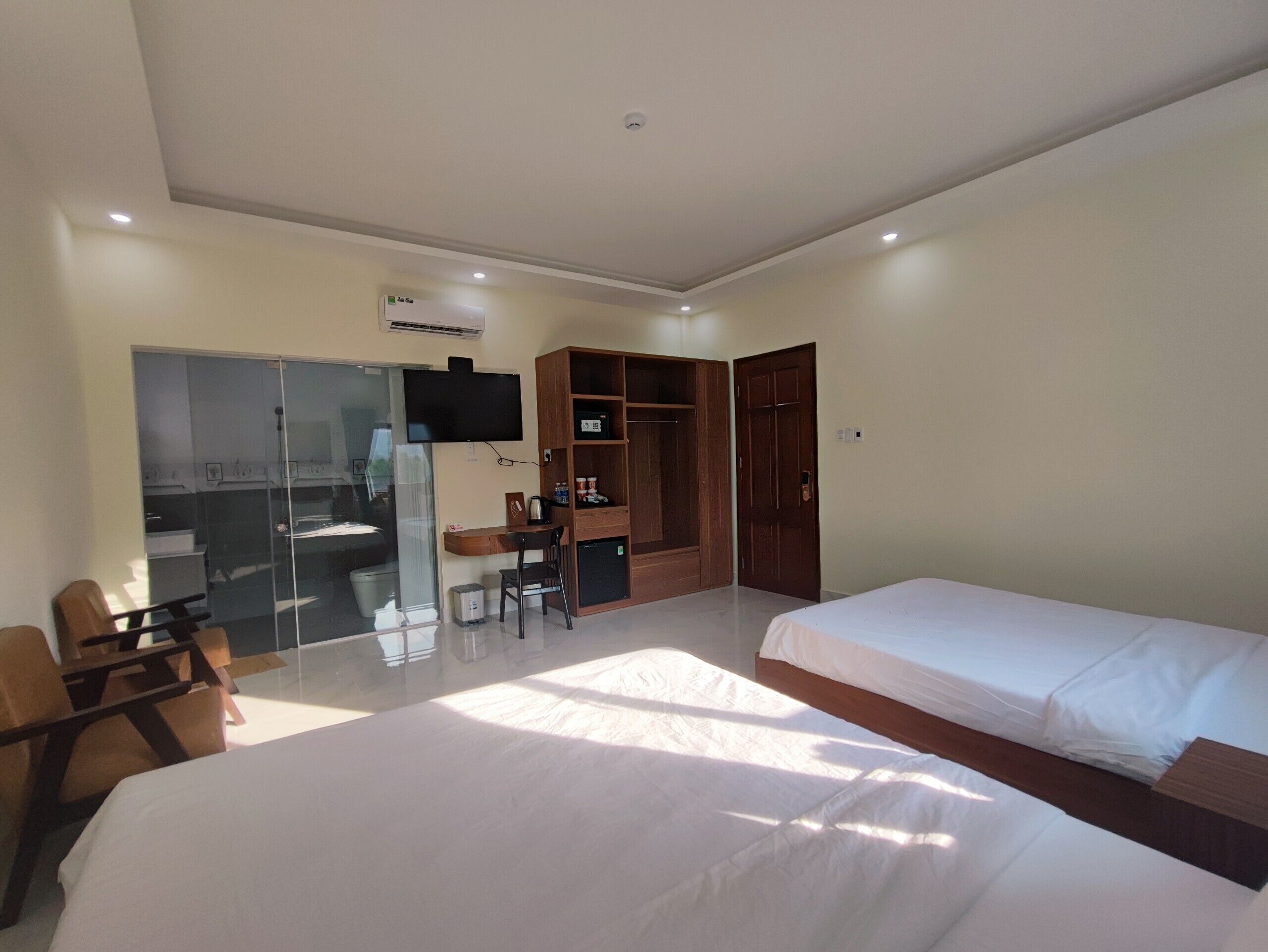 Een hotelkamer met twee bedden, een bureau, een stoel, een kledingkast en een televisie.