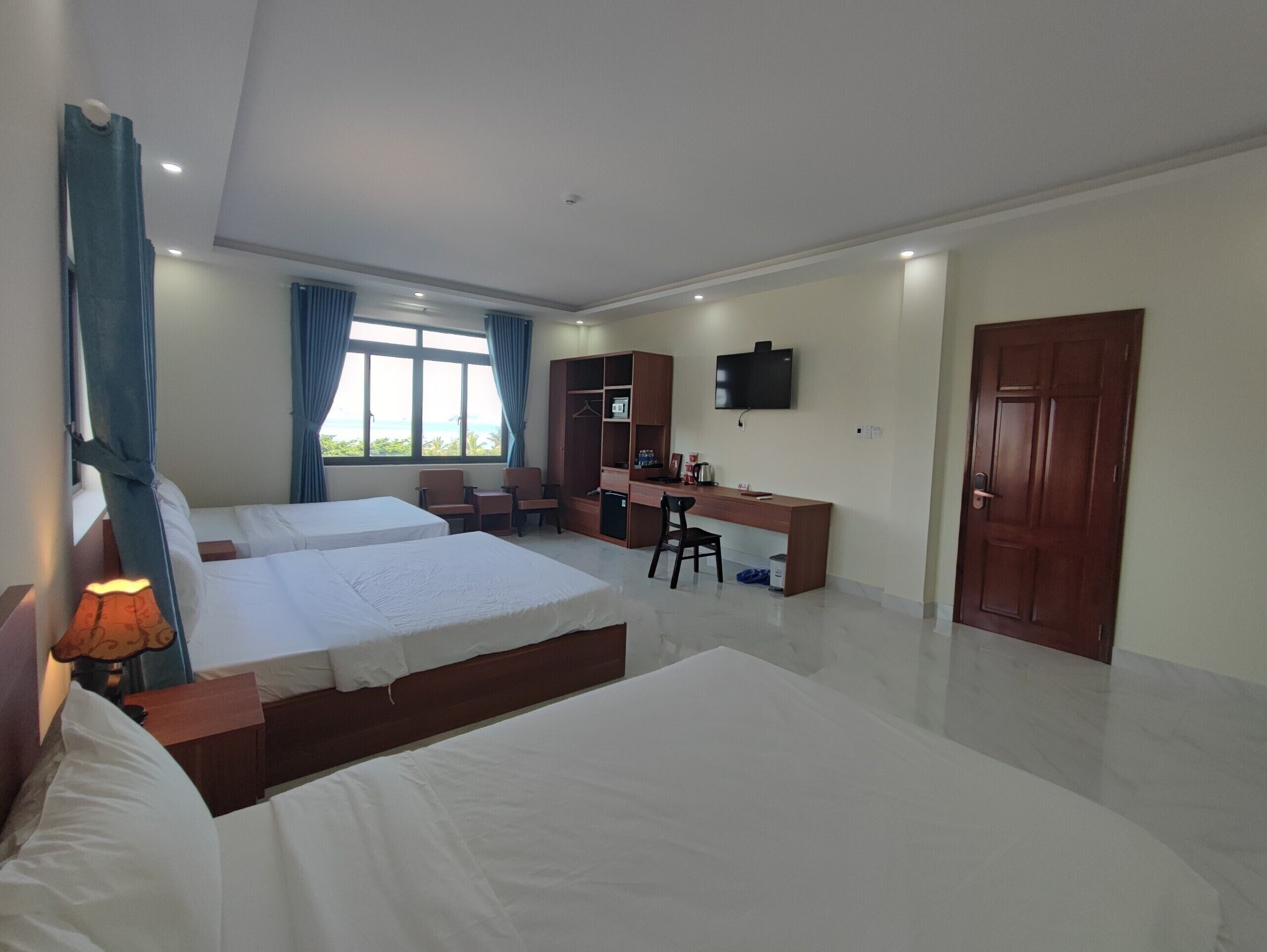 A hotel room with two beds, a desk, a TV, and a wardrobe.