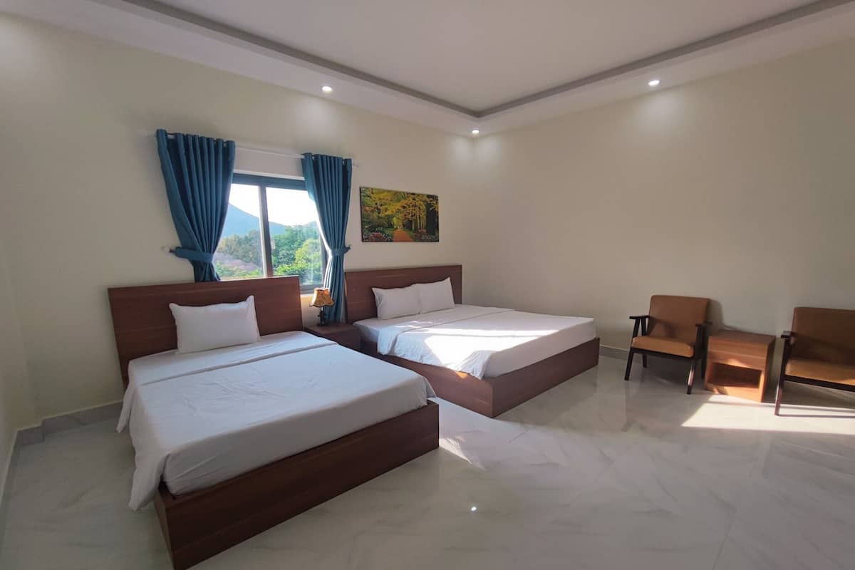 A hotel room with two beds, a chair, and a painting on the wall.