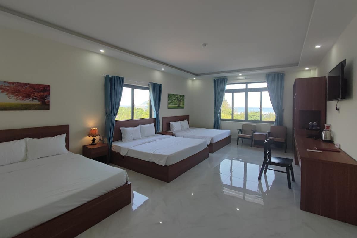 A hotel room with two beds, a desk, and a chair.