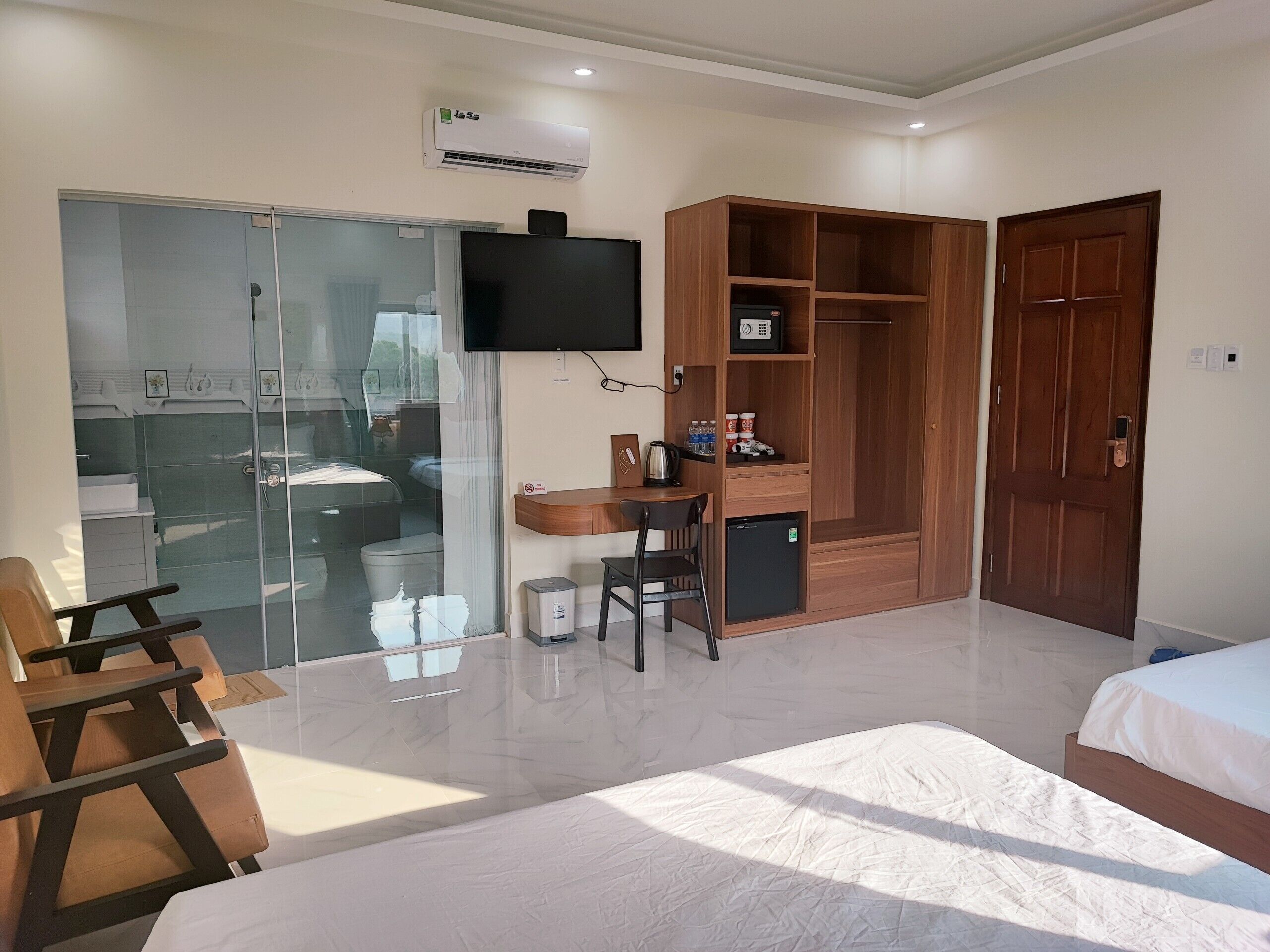 Una habitación de hotel con una cama, un escritorio, un armario y un televisor fijado a la pared.