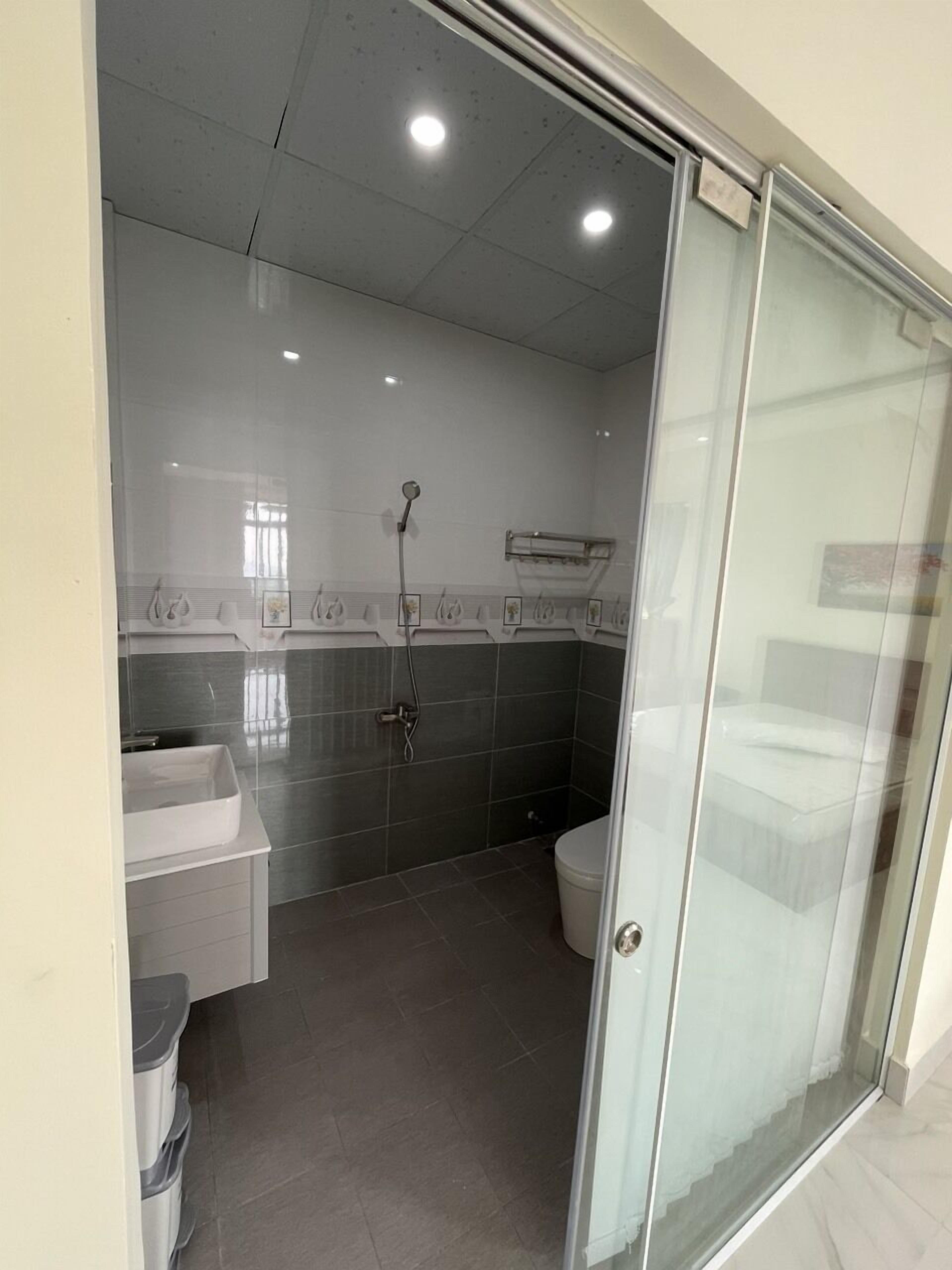 A modern bathroom with a glass shower enclosure, a toilet, and a sink.