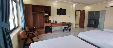 A hotel room with two beds, a desk, a chair, a wardrobe, and a television.