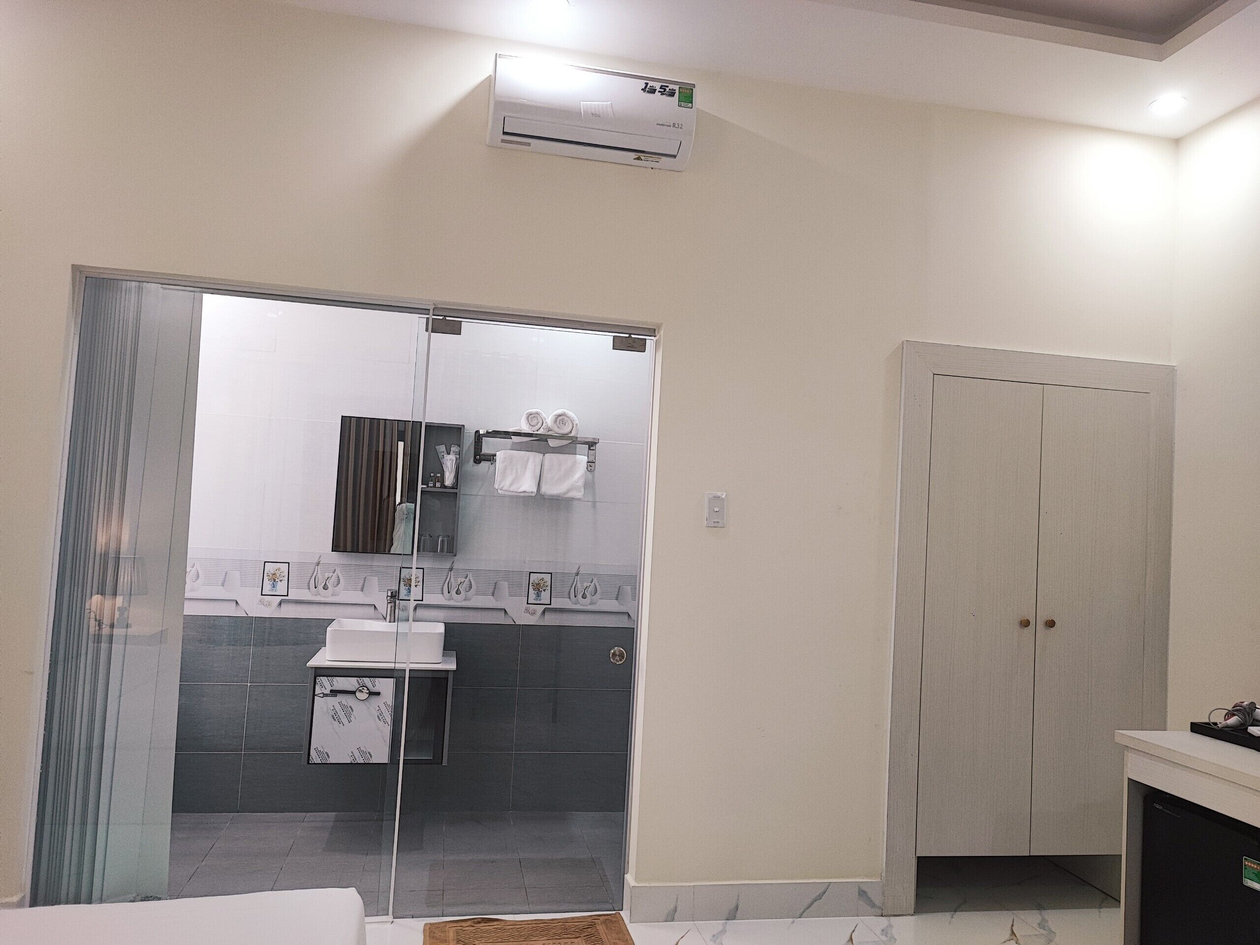A bathroom with a glass shower door, a sink, a towel rack, and a wardrobe.
