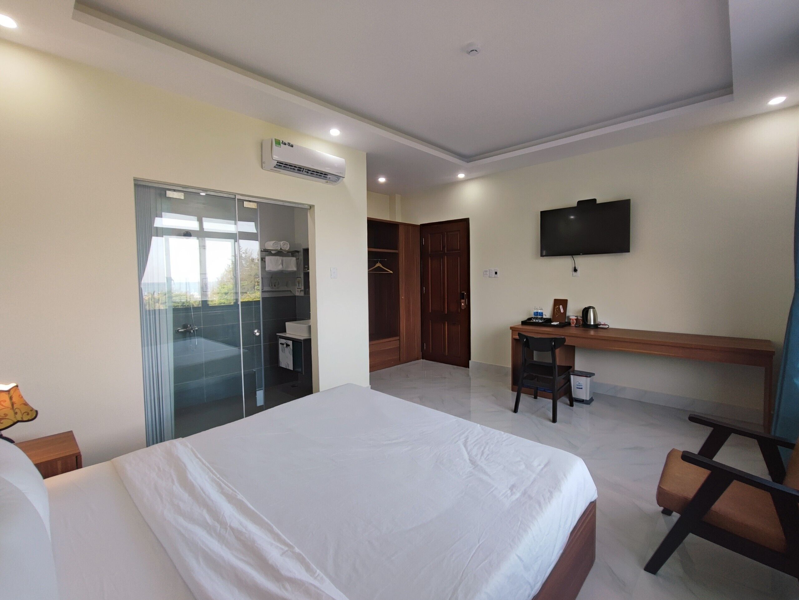A hotel room with a large bed, a desk, a TV, and a wardrobe.