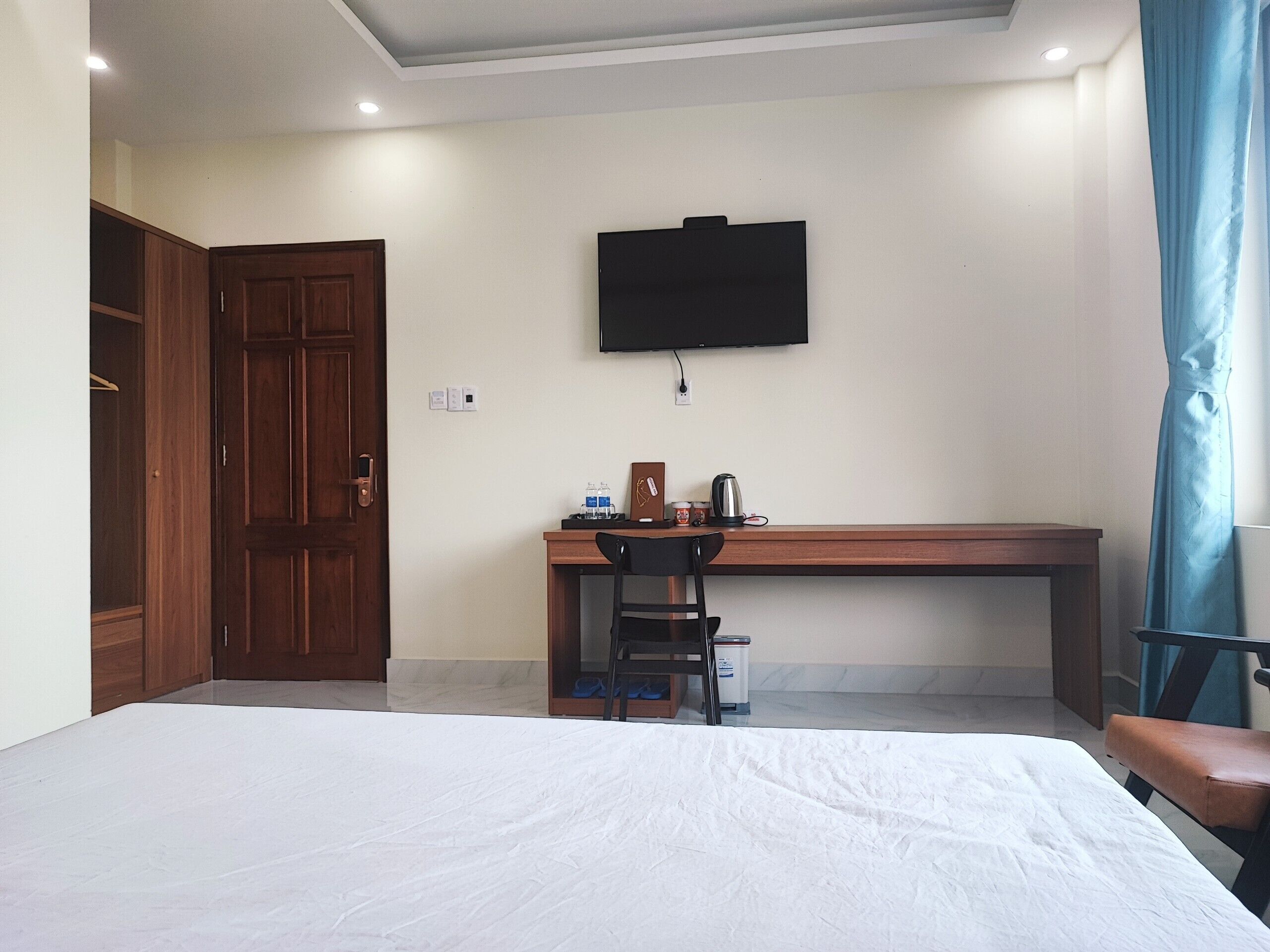 Une chambre d’hôtel comprenant un lit, un bureau avec une chaise, un téléviseur fixé au mur et une armoire.