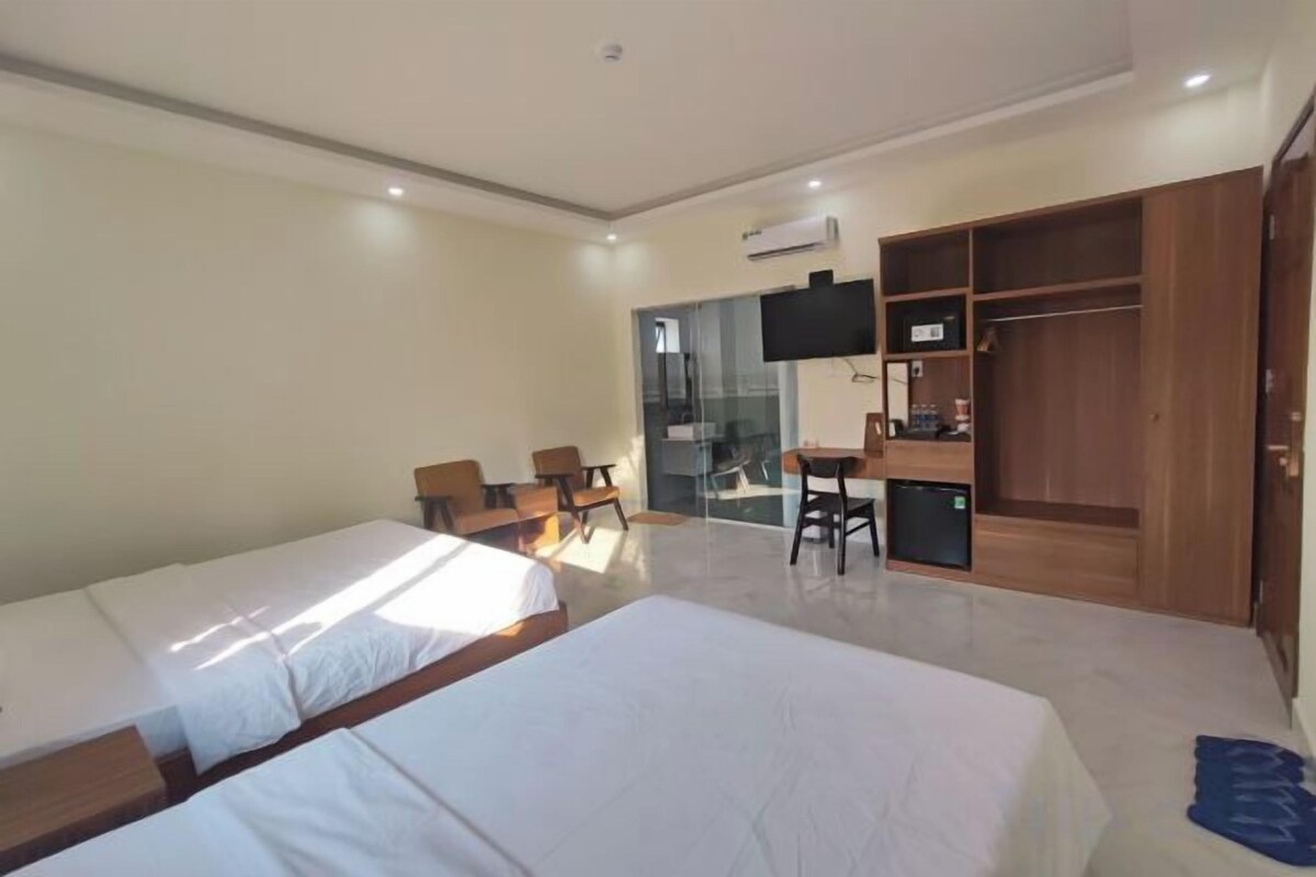 Een hotelkamer met twee bedden, een bureau, een televisie en een kledingkast.