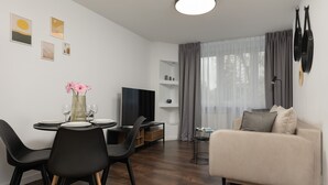 Una sala moderna con comedor, sofá, televisor y ventana con cortinas.