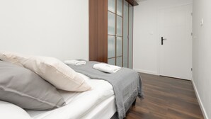 Un dormitorio con cama, almohadas, una colcha, un armario y una puerta.