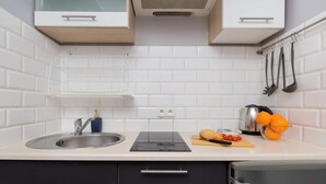 A modern kitchen with white subway tiles, a stainless steel sink, a black induction cooktop, and a built-in dishwasher.