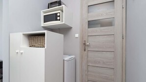 A compact room with a white wardrobe, a small white appliance, and a wooden door.