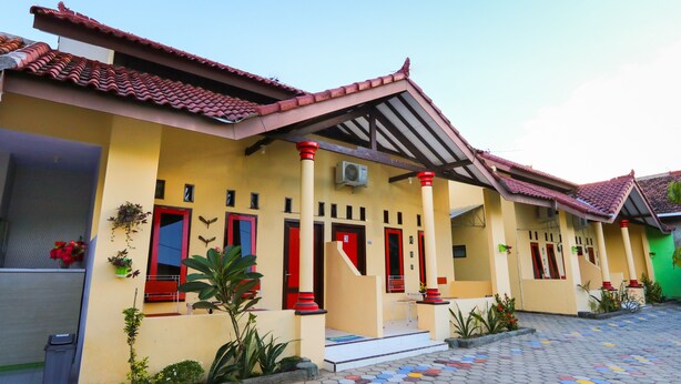 A building with a yellow facade, red doors, and a tiled roof. - Hotel O El Shaday Family Residence (Banyuwangi)
