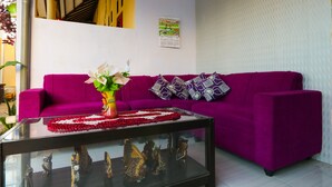A room with a purple sofa, a glass coffee table with decorative items, and a wall calendar. - Hotel O El Shaday Family Residence (Banyuwangi)